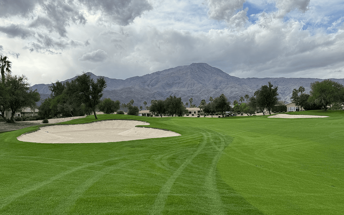 Fairway and sand bunker at Trilogy Golf Course with mountains in the background