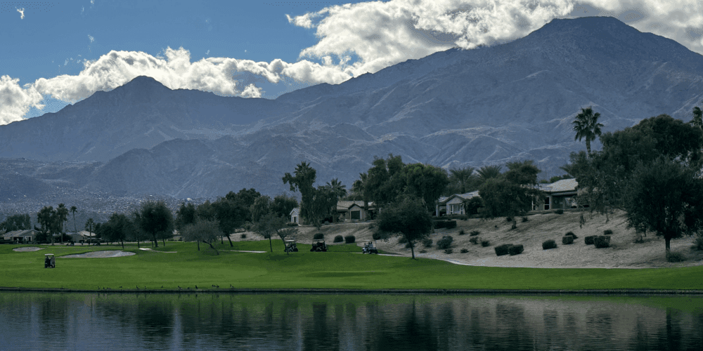 Golfers on the fairway at Trilogy Golf Course with water hazards and mountain scenery