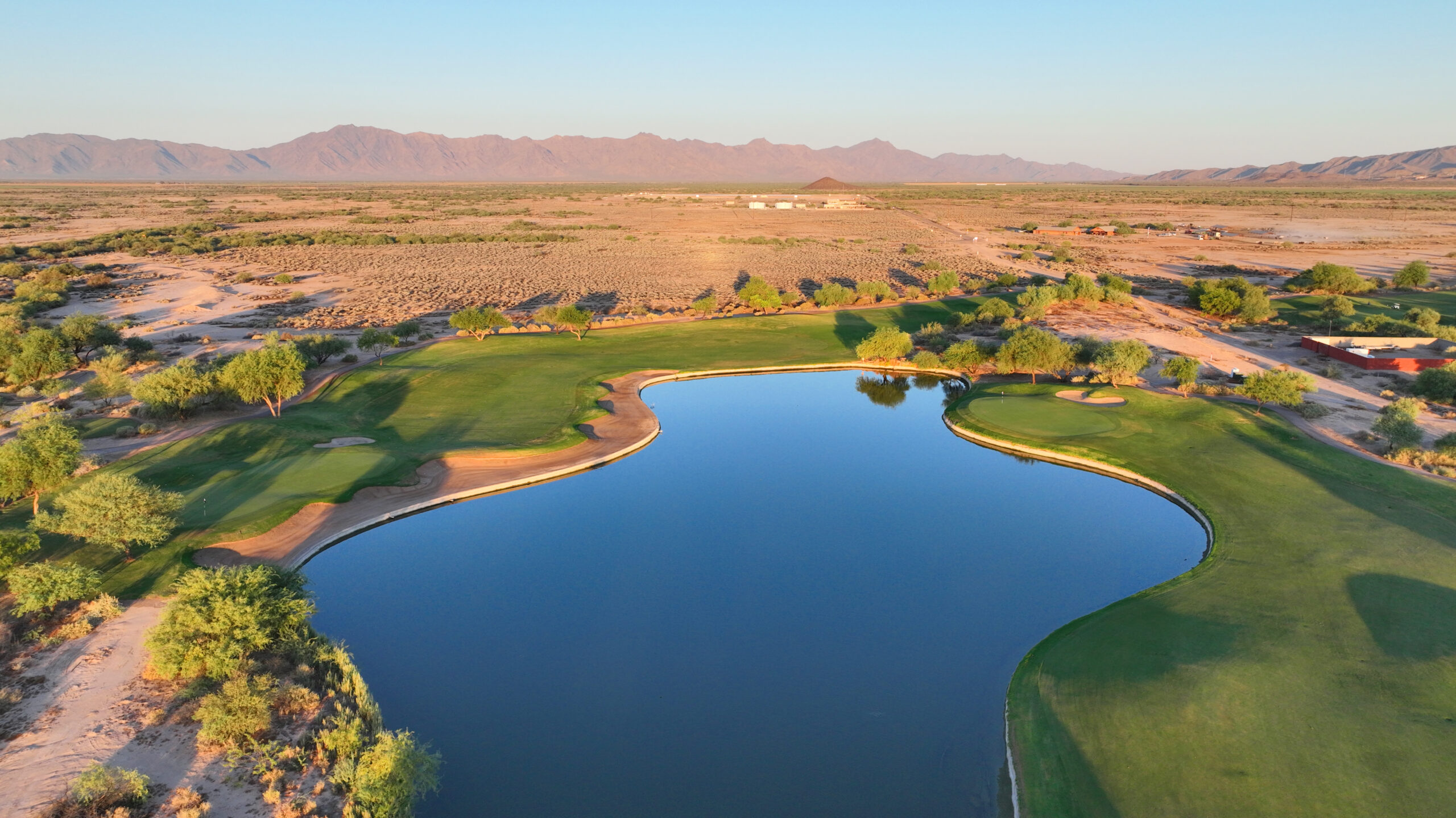 Golf course water feature surrounded by fairways and desert landscape