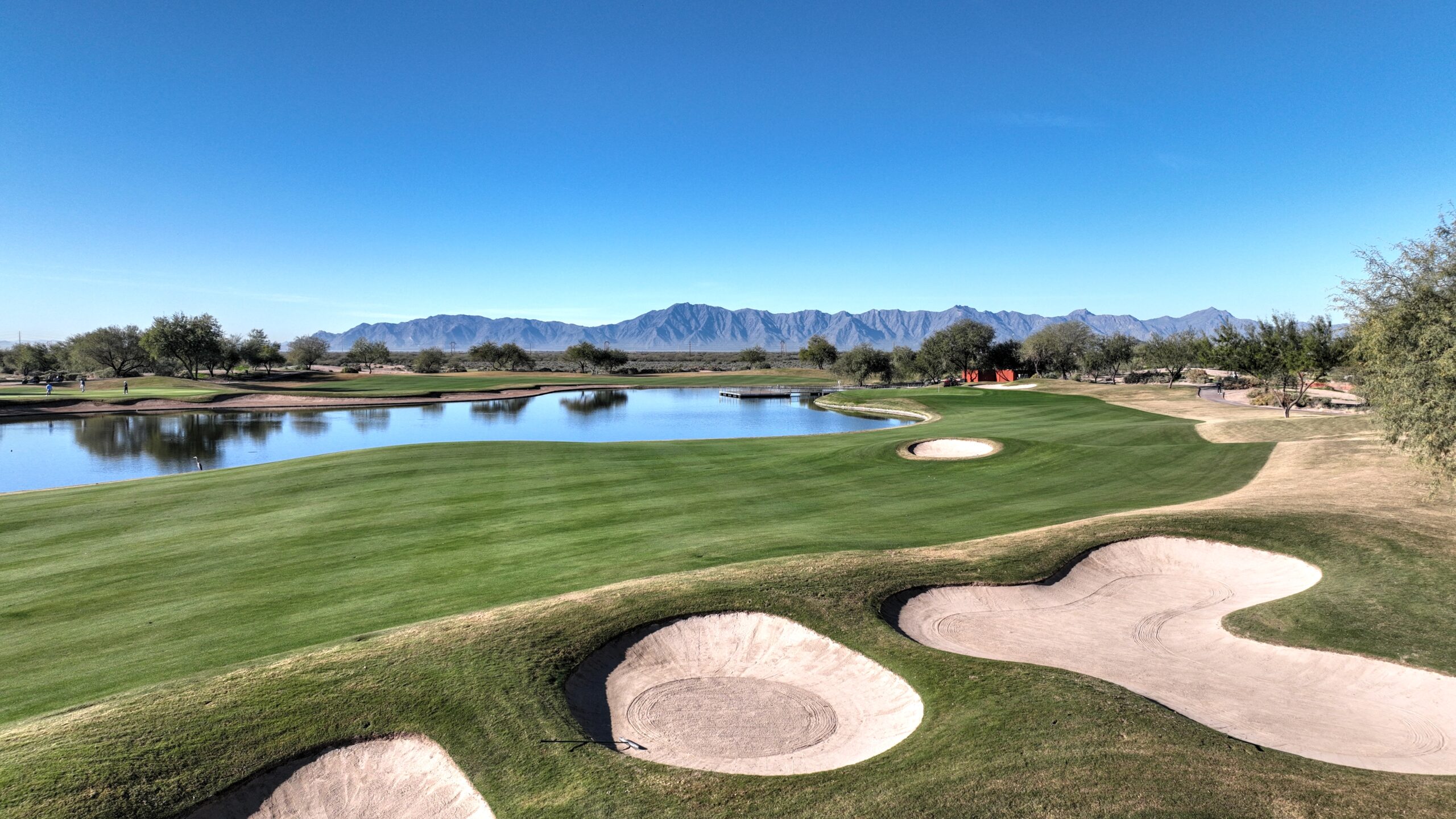 Whirlwind Golf Club fairway with sand bunkers, water hazard, and mountain backdrop