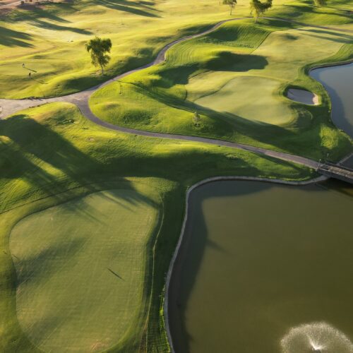 Aerial view of a golf course featuring greens, fairways, and connected water features